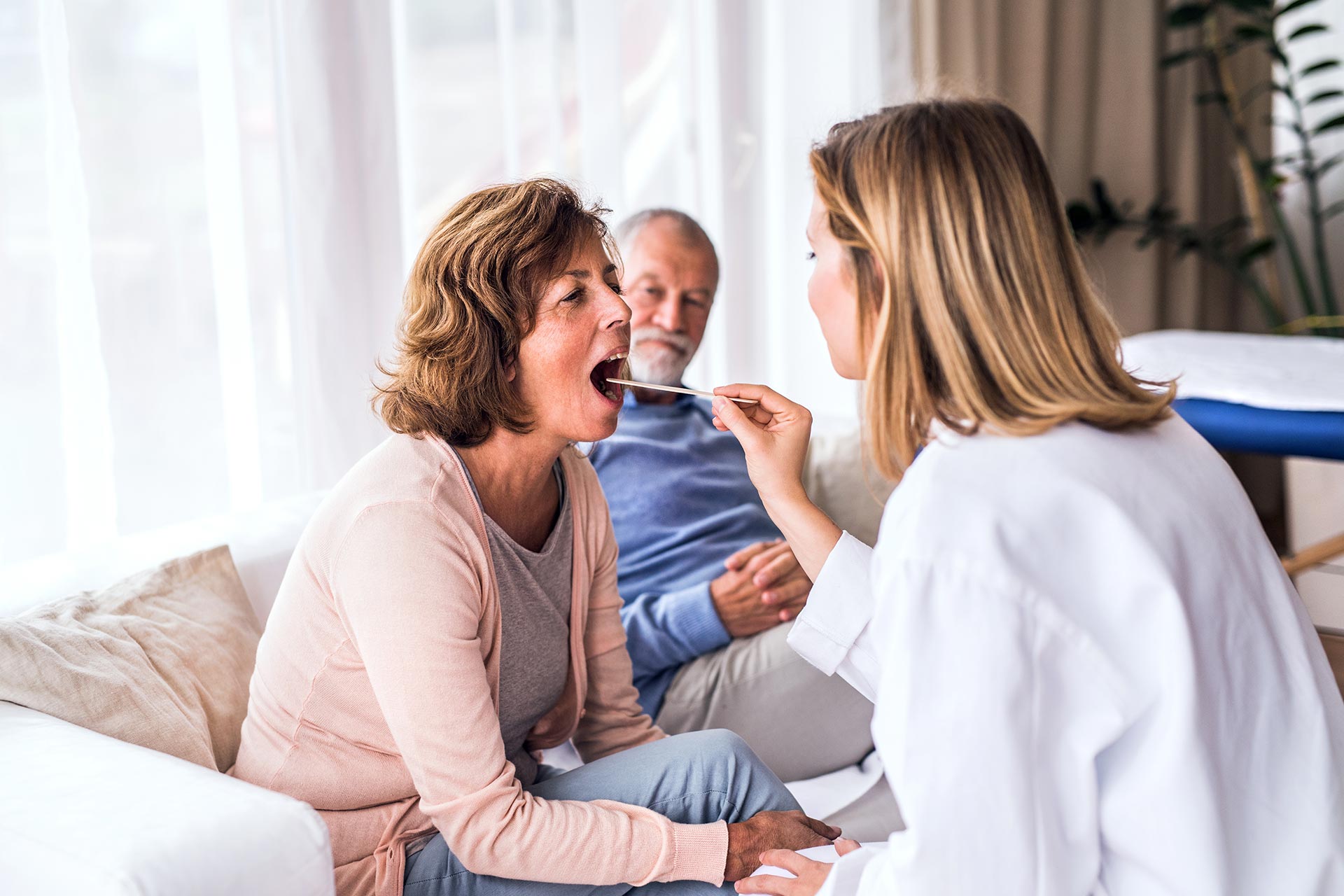 Ärztin untersucht Seniorin bei einem Hausbesuch im Wohnzimmer
